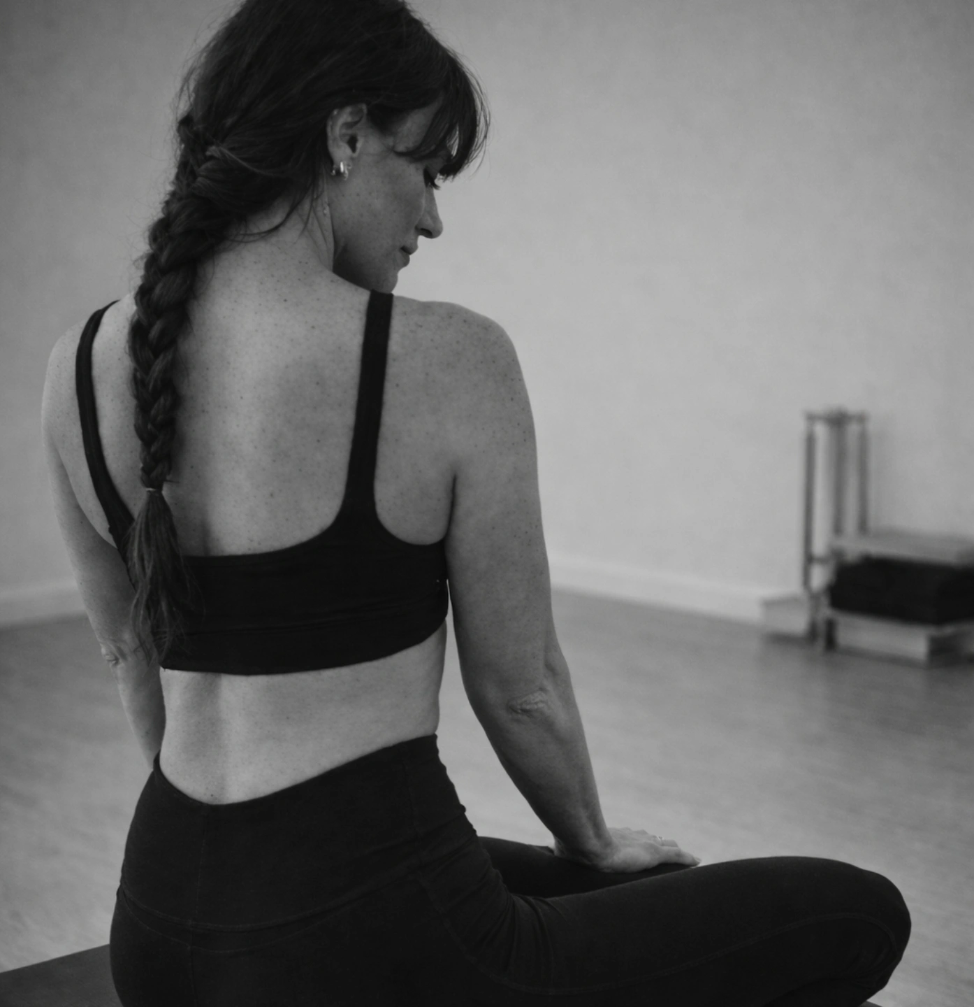 Rae Carpenter seated meditation in Reformer studio black and white